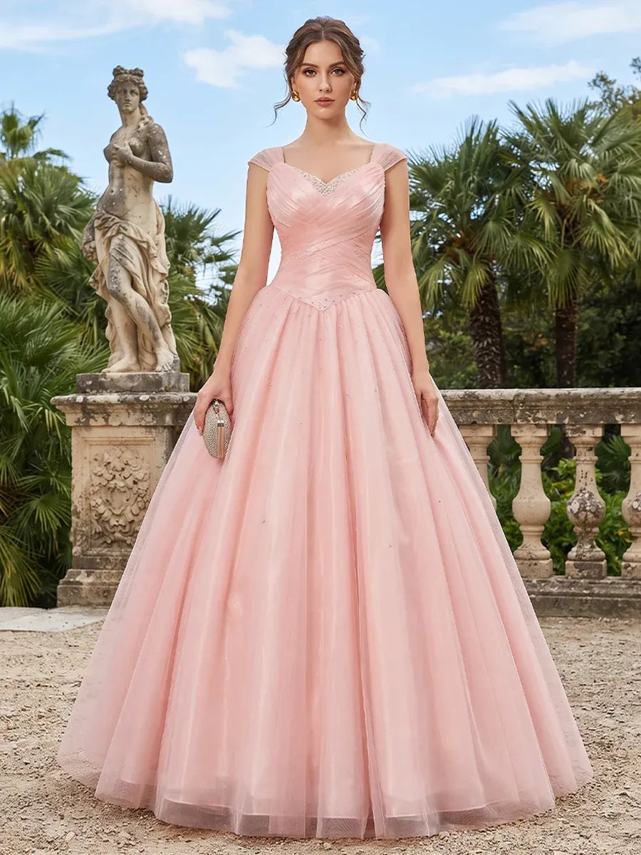 Front view of Loverlm blush pink ball gown prom dress with sweetheart neckline, cap sleeves, ruched bodice and full tulle skirt