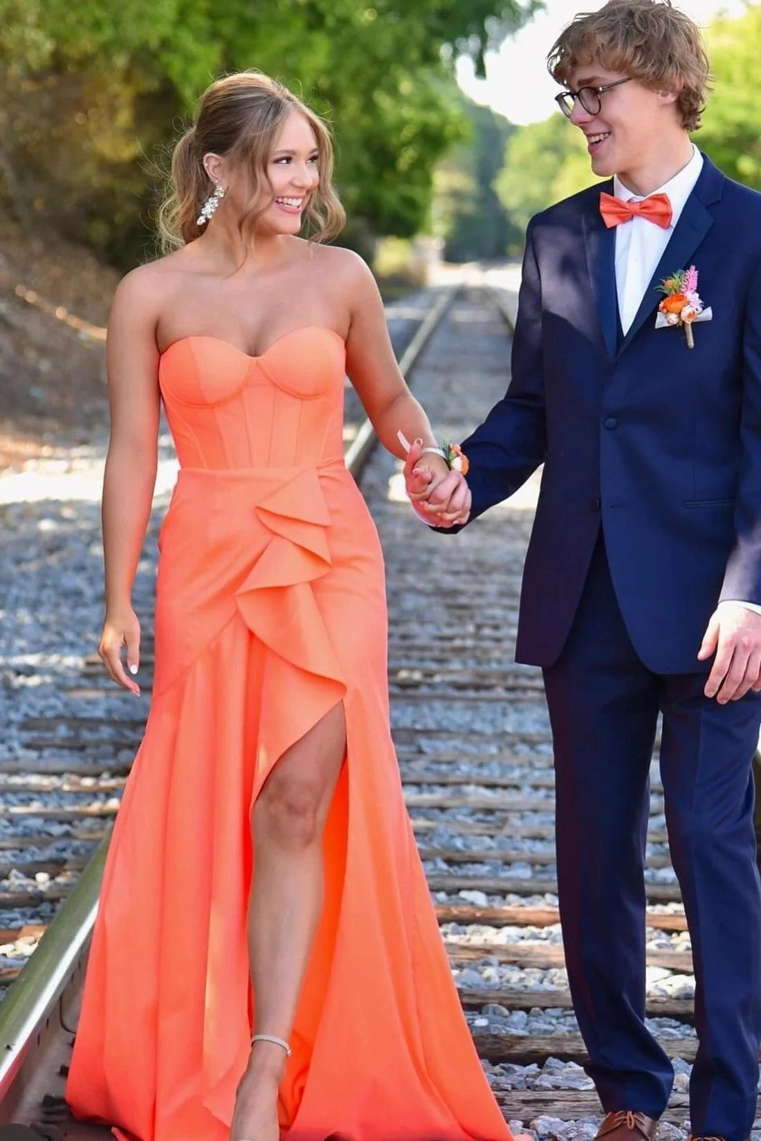 Loverlm coral orange strapless prom dress with a sweetheart corset bodice, cascading front ruffles, high leg slit, and floor-length skirt.