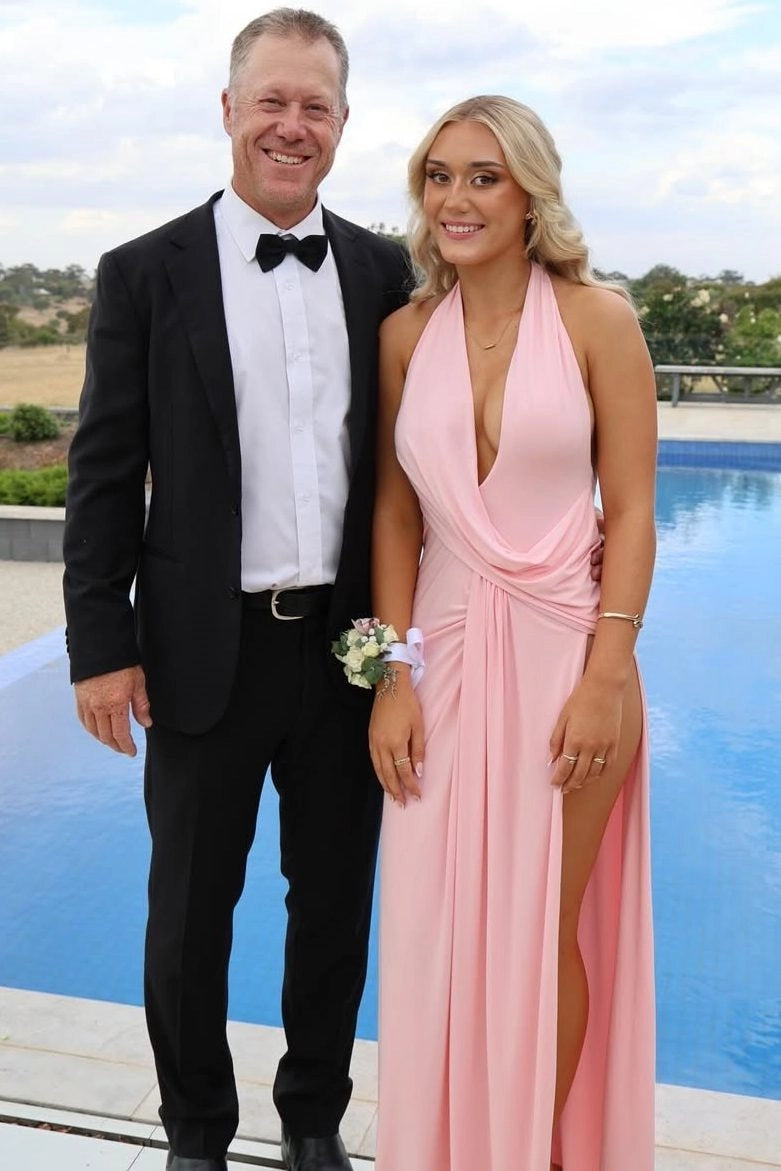 Front view of Loverlm light pink halter prom dress with a plunging V-neckline, draped waist and a floor-length skirt with a thigh-high slit.