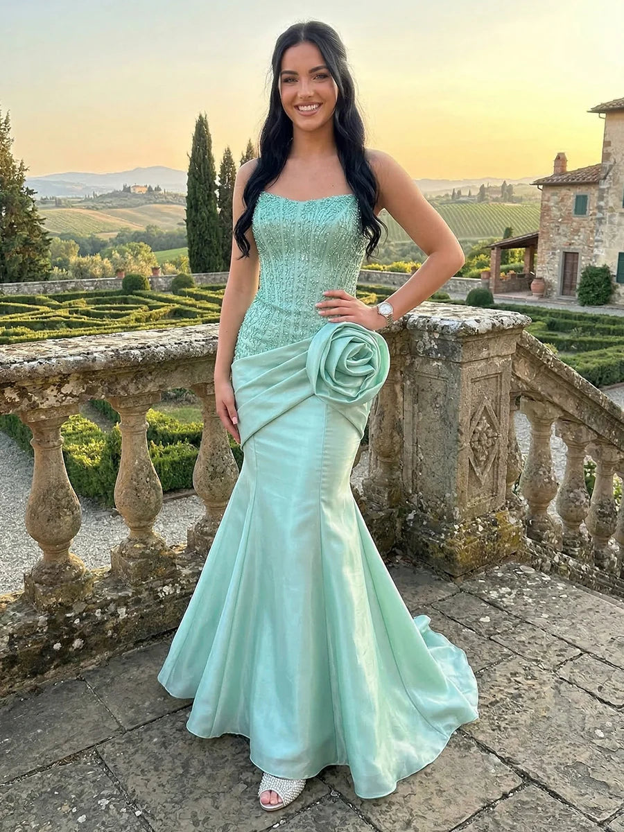 Mint green strapless mermaid prom dress with beaded corset bodice, sweetheart neckline, oversized 3D floral rosette, satin draping and sweep train by Loverlm