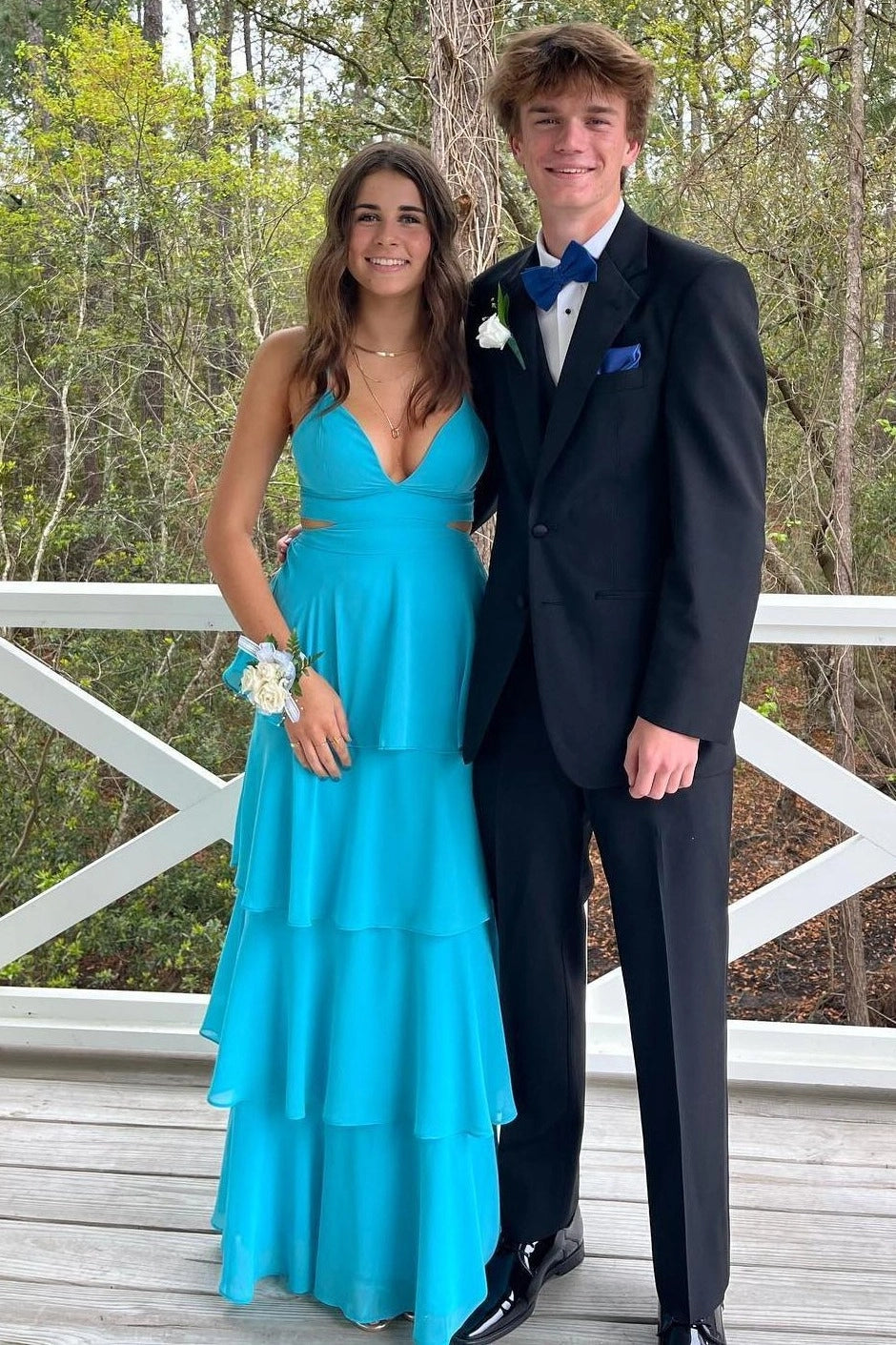 Front view of a Loverlm turquoise chiffon A-line prom dress with a V-neckline, spaghetti straps, side cutouts, and tiered floor-length skirt.