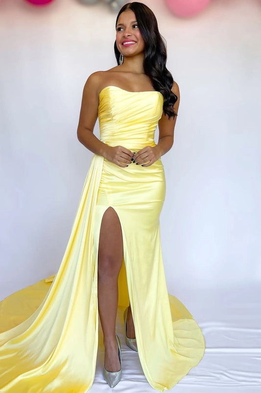Front view of a Loverlm yellow satin mermaid prom dress with a strapless ruched bodice, high side slit, waist sash, and floor-length train.